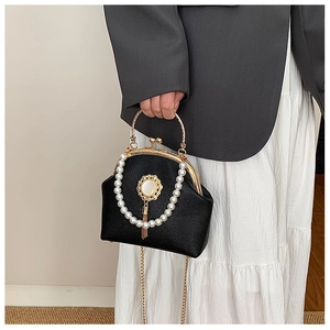 Detail of black lychee leather shell bag with pearl trim and golden fringe pendant
