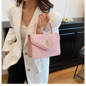 Detailed view of pink textured leather handbag with gold twist lock and round handle