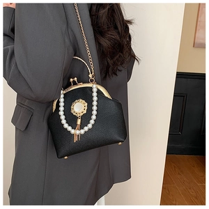 Detail of vintage black shell bag with pearl handle and tassel on grey blazer