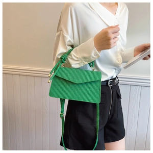Détail du sac bandoulière tissé vert avec boucle dorée et poignée nouée élégante