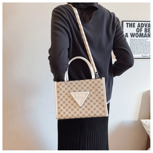 Detail view of large tote bag with geometric pattern and white handle on shoulder