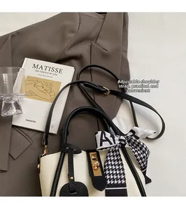 Dettaglio della borsa a secchiello bicolore con chiusura dorata e foulard stampato