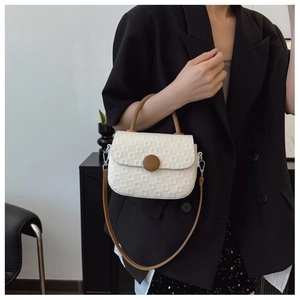 Detailed view of a white textured crossbody bag with a large brown buckle detail