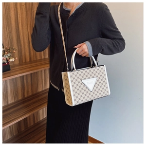 Detail of beige monogram tote bag featuring leather handles and adjustable shoulder strap
