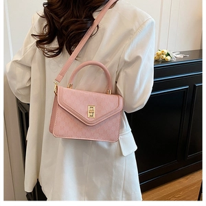 Pink square handbag with golden twist lock shown worn as a crossbody bag for women