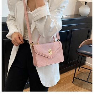 Pink leather handbag with gold square lock shown on a stylish modern indoor cabinet