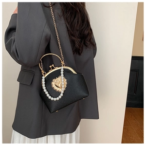 Detail of black pebbled leather shell bag with gold heart ornament and pearl chain