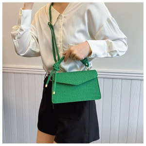 Détail du sac à main tissé vert avec bandoulière corde et boucles dorées
