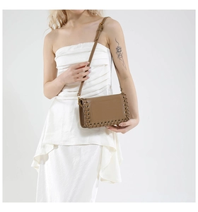 Detail of tan polished leather shoulder bag featuring decorative woven edge stitching