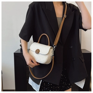 Detail of cream crossbody bag with textured geometric pattern and brown accents