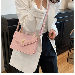 Detail of pink crossbody bag with subtle M-letter pattern and golden metal turn-lock clasp