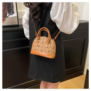 Braune Muscheltasche mit Monogramm, von einem Model elegant als Umhängetasche getragen