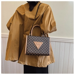 Close-up of vintage brown monogram pattern and leather logo on large tote bag