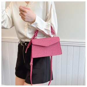 Détail de la texture tissée rose sur un sac bandoulière rectangulaire avec rabat