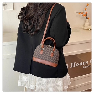 Details der eleganten Muscheltasche mit braunem Patchwork-Muster und Lederriemen