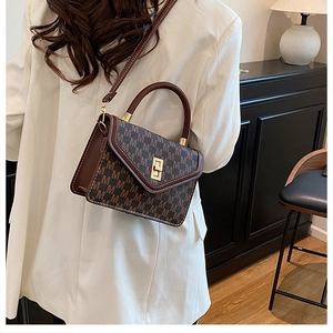 Detail of vintage monogram shoulder bag with gold clasp and brown leather patchwork