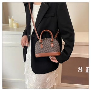 Detailansicht der Mini-Muscheltasche mit braunem Geometriemuster und Ledergriffen