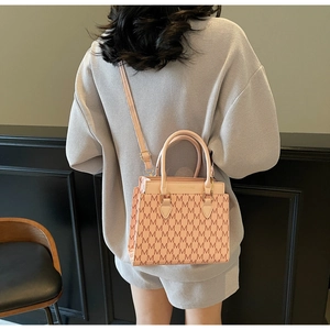 Pink tote bag detail with monogram pattern, crossbody strap and golden hardware