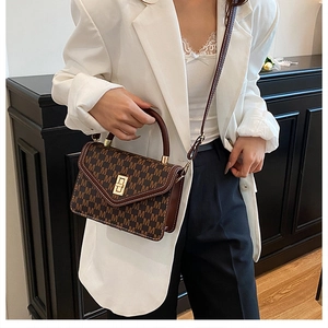 Detailed view of dark brown crossbody bag featuring repeated M pattern and gold twist lock