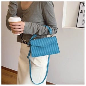 Détail du sac à main tissé bleu montrant la texture avec poignée nouée et bandoulière