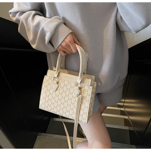 Détail d'un sac cabas crème avec motifs M marron et accessoires métalliques dorés