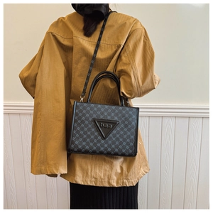 Detail of trendy large tote bag featuring geometric print and triangular bag logo plate