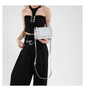 Dettaglio borsa a tracolla argento con cuciture geometriche e borchie metalliche