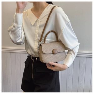 Detail of a beige checkered crossbody bag with brown handle worn by a model in a studio