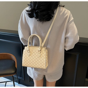 Model showing a beige vintage tote bag with M-pattern jacquard and leather strap