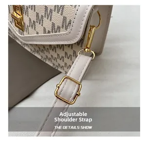 Detail of golden adjustable buckle on cream PU leather strap with letter pattern