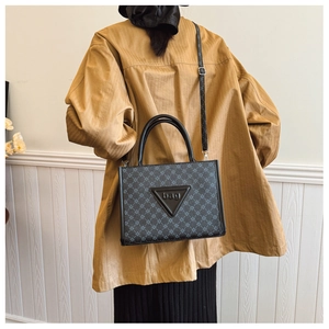 Detailed view of crossbody tote bag with geometric pattern and triangular logo patch