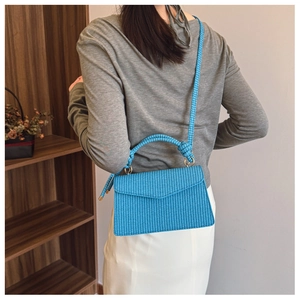 Détail du sac à main tissé bleu vif avec poignée en corde épaisse et fermoirs dorés