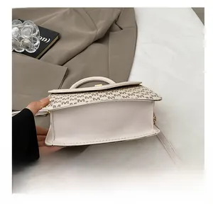 Detail showing the textured wear-resistant flat bottom of the cream crossbody bag