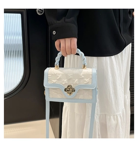 Detail of light blue crossbody bag featuring woven texture and gold clover twist lock