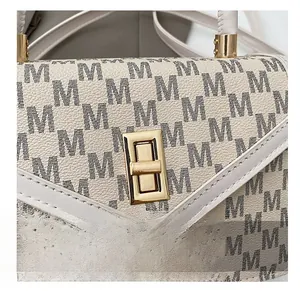 Macro shot of rectangular gold twist lock and M-letter print on beige shoulder bag