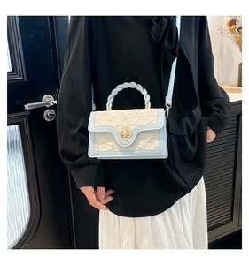 Detail of light blue crossbody bag featuring woven handle and golden floral twist lock
