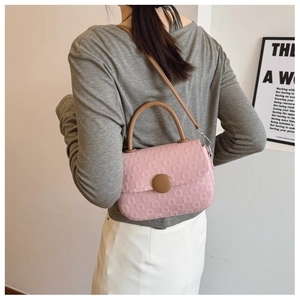 Detail of pink embossed fabric handbag showing texture and brown shoulder strap