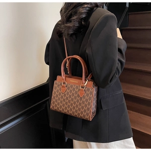 Detail of vintage brown monogram handbag shown on model against a stylish staircase
