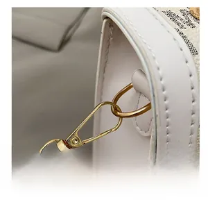 Macro shot of gold-tone metal clasp and beige canvas with elegant letter print