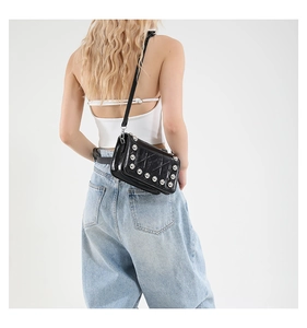 Dettaglio di borsa punk nera con borchie argentate e cuciture a croce decorative