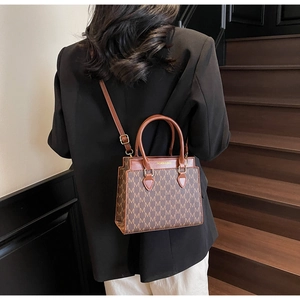 Gros plan sur un sac cabas vintage marron avec motif de lettres et détails dorés