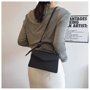 Détail du sac bandoulière noir avec texture géométrique et poignée ronde en métal