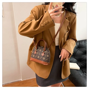 Detailansicht der braunen Muscheltasche mit Monogramm-Muster und Lederbesatz