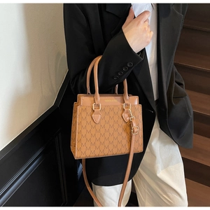 Détail d'un sac cabas marron texturé avec lettrage doré et bandoulière réglable
