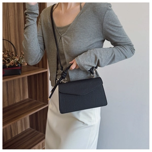 Détail de la texture verticale et de la poignée nouée de ce sac carré noir chic