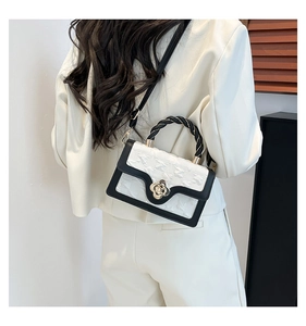 Detail of a vintage floral clasp on a black and white textured crossbody handbag