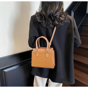 Detail shot of vintage brown tote bag with M-pattern print and long adjustable strap