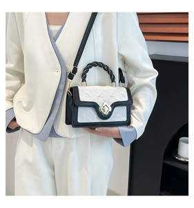 Detail of a chic black and white handbag with floral buckle on a white blazer