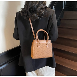 Détail d'un sac bandoulière marron avec texture monogramme classique et logo imprimé