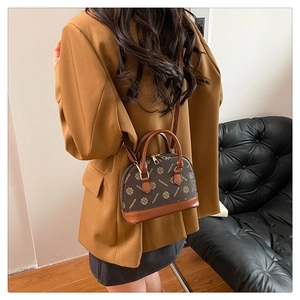 Detailansicht der braunen Monogramm-Schalen-Tasche, die stilvoll crossbody getragen wird